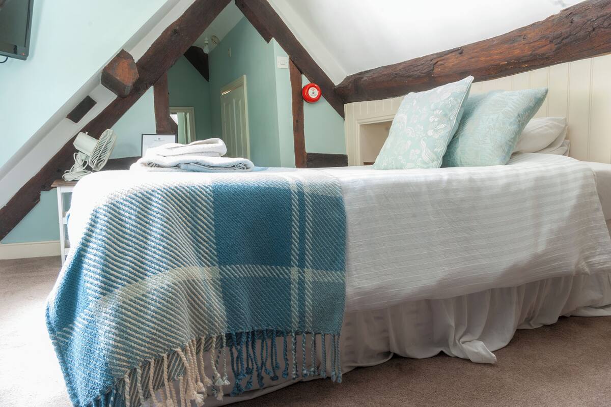 A bedroom with a bed, a fan, and a door.