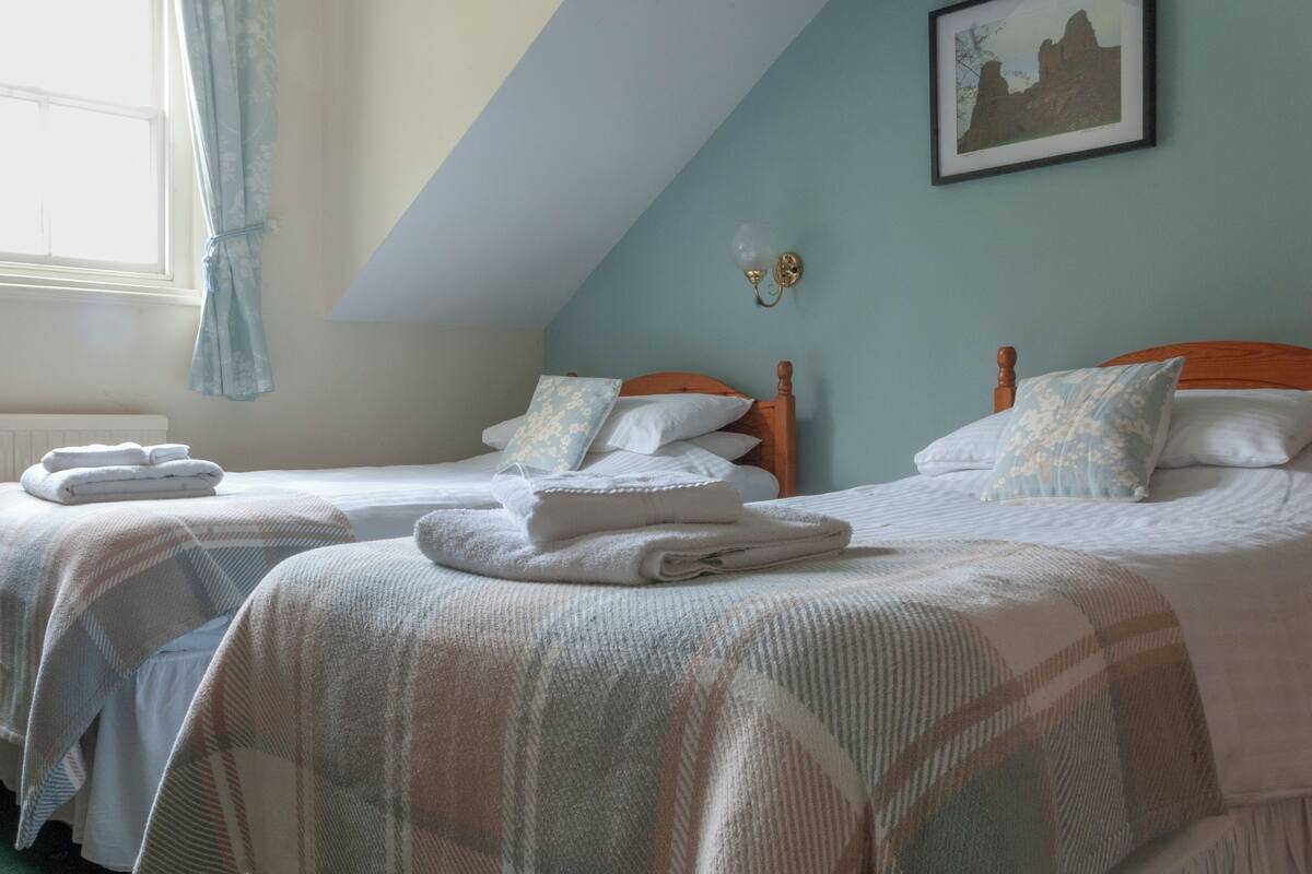A bedroom with two beds, each with a wooden headboard, white bedding, and a framed picture on the wall.