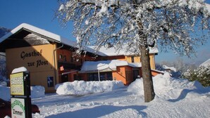 Ein Gebäude mit einem Schild, auf dem 'Gasthof zur Post' steht, umgeben von Schnee.