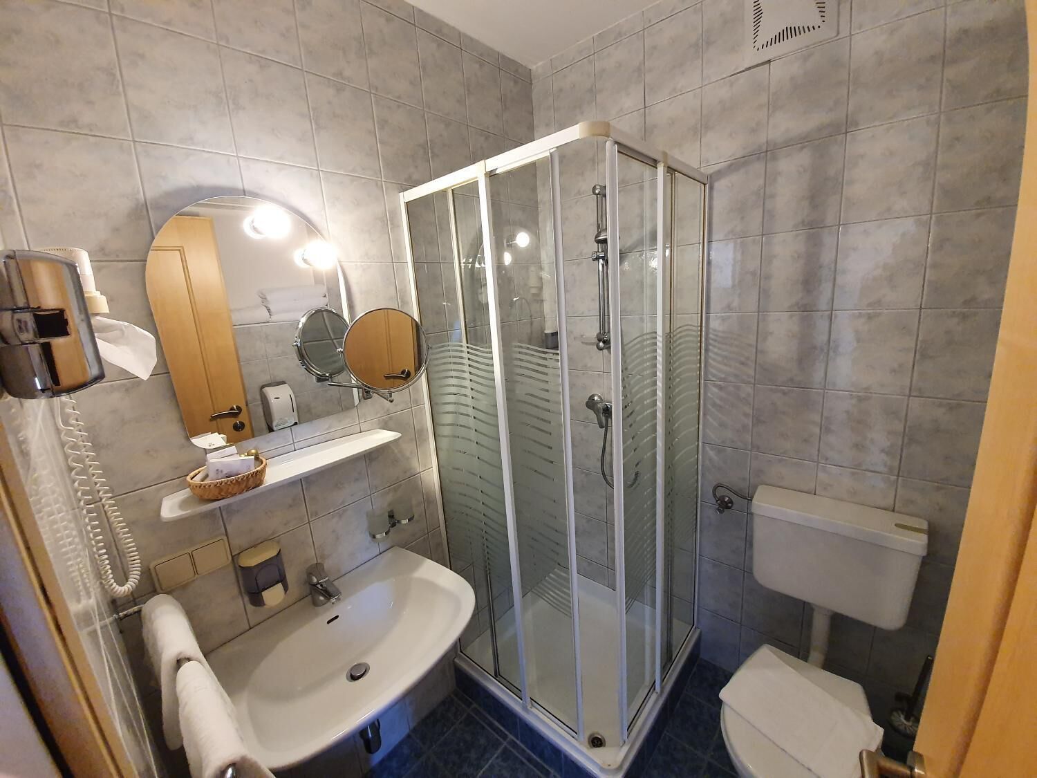 Un baño moderno con ducha de vidrio, lavamanos, inodoro y espejo.