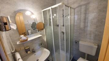 Un baño moderno con ducha de vidrio, lavamanos, inodoro y espejo.