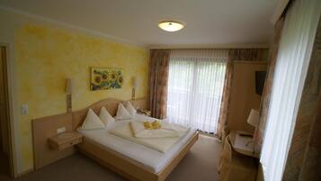 Ett hotellrum med en stor säng, ett nattduksbord, en lampa, en tavla och ett fönster med gardiner.
