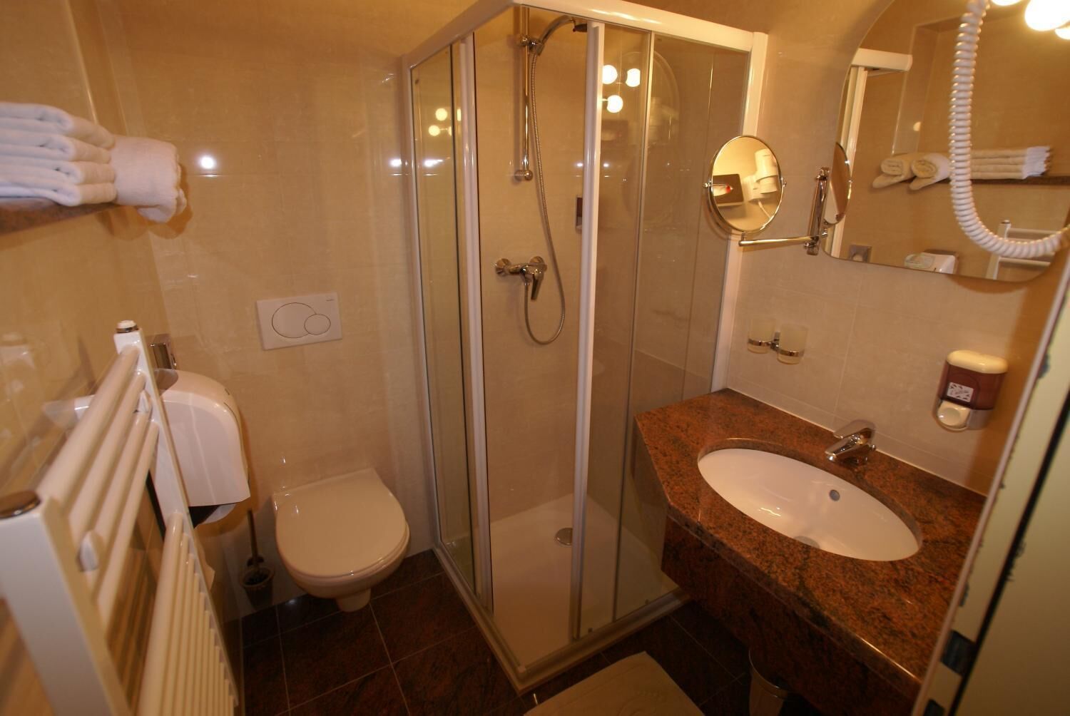 A modern bathroom with a glass-enclosed shower, a white toilet, and a granite countertop sink.