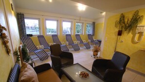 Ein Zimmer mit einer Couch, zwei Sesseln, einem kleinen Tisch und einer Reihe von gestreiften Loungesesseln.