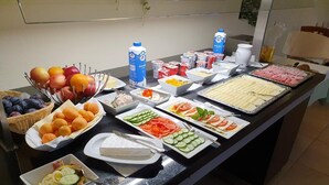 Ein Buffet mit verschiedenen Speisen, darunter Obst, Käse und Salate.