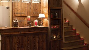 Una cocina de madera con lámparas colgantes, un reloj y una escalera con luces rojas.