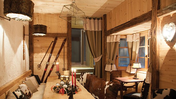 Interior acogedor de una cabaña de madera con una mesa de comedor para dos, un sofá y una silla.