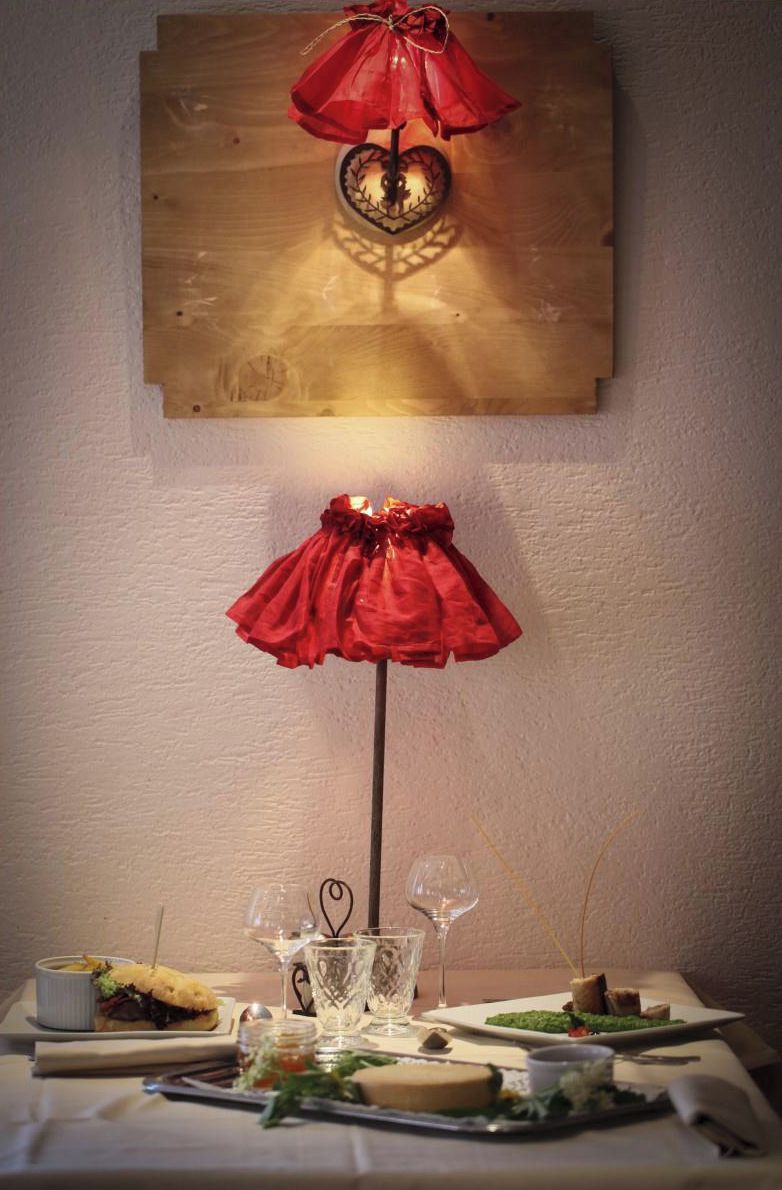 Una mesa dispuesta con diversos platos, vasos y cubiertos, con un objeto decorativo rojo con forma de paraguas sobre ella.