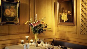 Una mesa de comedor dispuesta con un jarrón de flores, velas, copas de vino y pan.