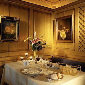 Une table à manger dressée avec un vase de fleurs, des bougies, des verres à vin et du pain.