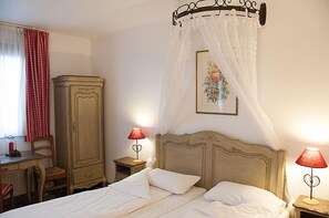 Ein Schlafzimmer mit einem Bett, zwei Nachttischlampen, einem Nachttisch, einem Holzschrank, einem Stuhl und einem Fenster mit roten Vorhängen.