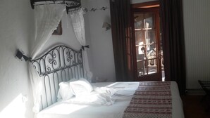 Una cama con ropa blanca, una colcha estampada y un cabecero de metal.