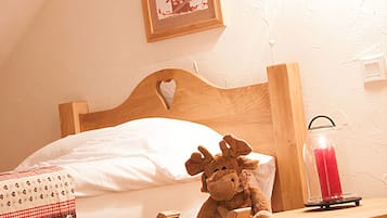 Un letto in legno con testiera a forma di cuore, un peluche, un portacandele in vetro e un quadro appeso al muro.