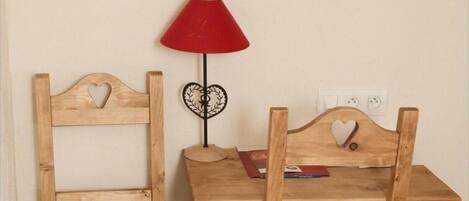 Two wooden chairs with heart-shaped cutouts on the backrests and a small table between them.