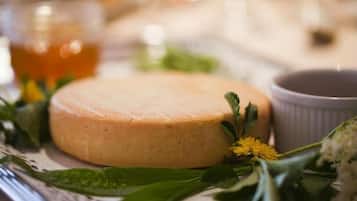 A round cheese on a plate with a cup and some greenery.