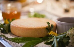 A round cheese on a plate with a cup and some greenery. - The Originals Boutique, Hôtel La Ferme du Pape, Eguisheim (Eguisheim)