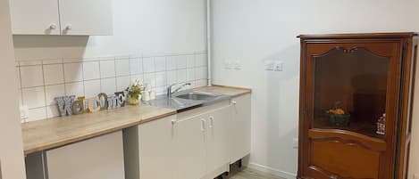 A kitchen with white cabinets, a wooden cabinet with glass doors, a sink, and a countertop with a vase and decorative items.