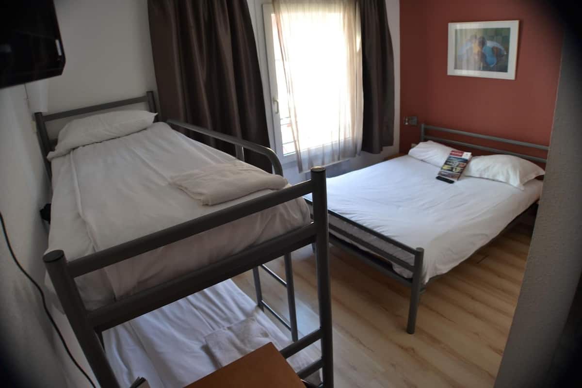 A room with two beds, one bunk bed and one single bed, with a window and curtains.
