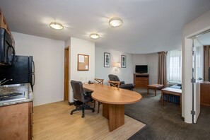 A hotel room with a kitchen area, a dining table with chairs, a TV, and a window with curtains. - Candlewood Suites Perrysburg by IHG (Perrysburg)