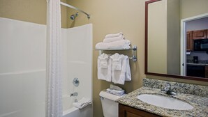 A bathroom with a bathtub, toilet, sink, and a mirror.