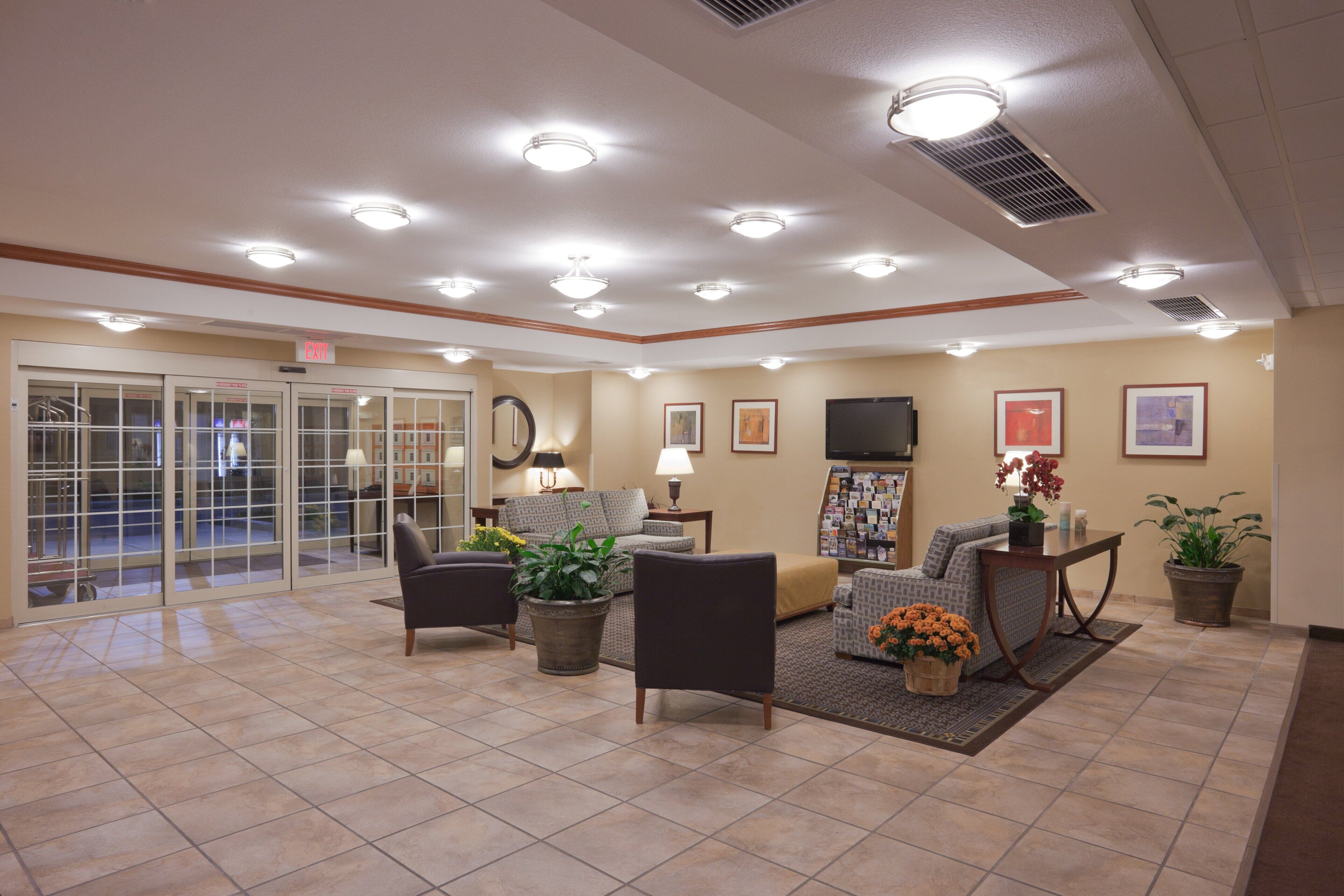 A lobby with multiple seating areas, a fireplace, and a wall-mounted television.