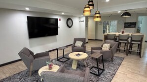 A modern living room with grey sofas, a coffee table, and a TV mounted on the wall.