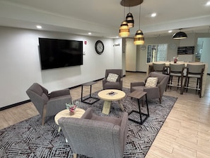A modern living room with grey sofas, a coffee table, and a TV mounted on the wall. - Candlewood Suites Perrysburg by IHG (Perrysburg)
