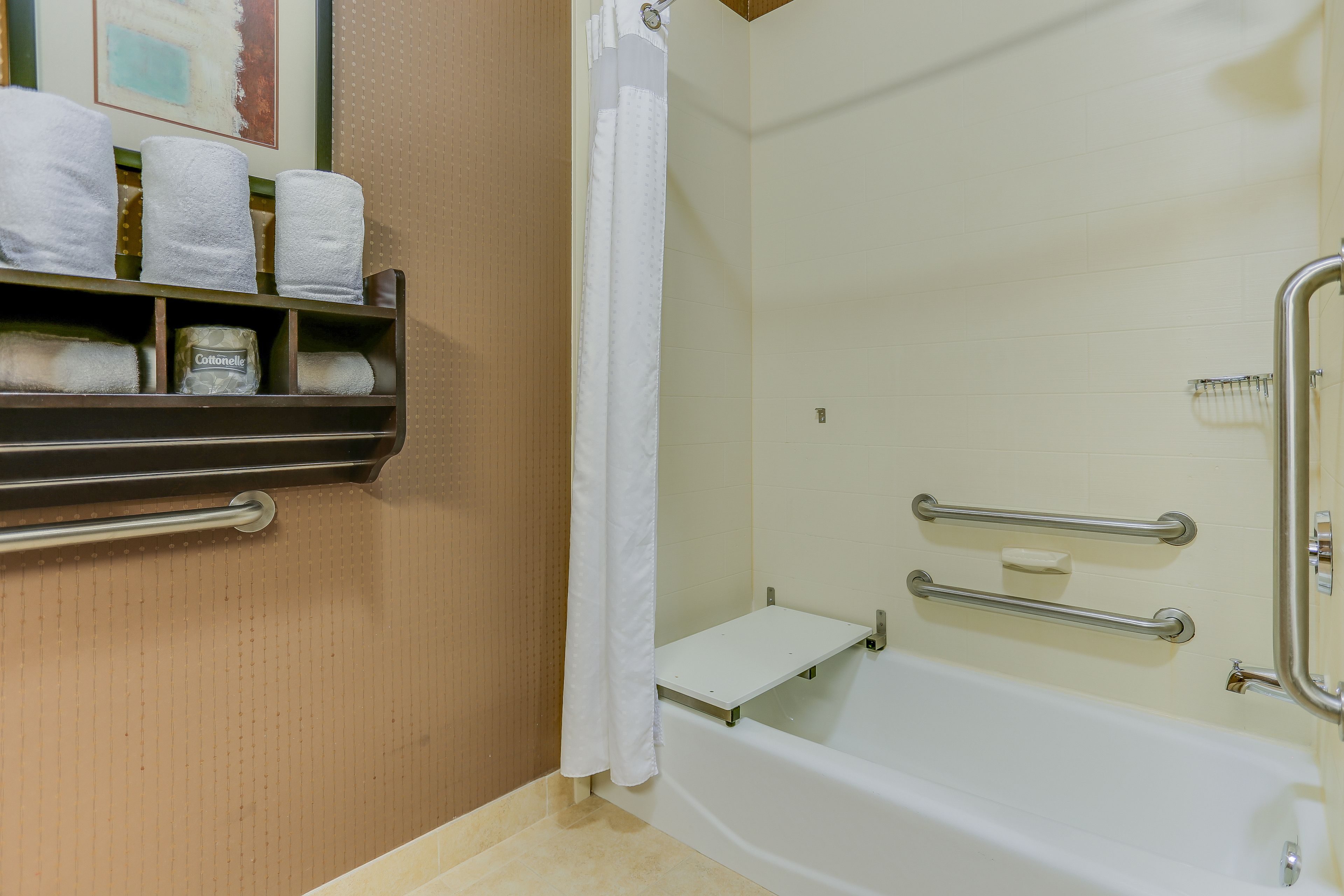 Une salle de bain avec une baignoire, un rideau de douche, une étagère avec des serviettes et un porte-rouleau de papier toilette.
