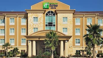 A Holiday Inn Express & Suites hotel with a symmetrical facade, multiple windows, and a central entrance with columns.