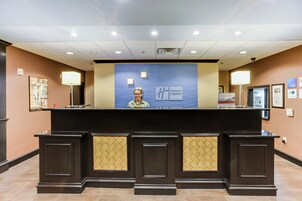 A reception desk with a Holiday Inn Express sign, a security camera, and a framed welcome sign.