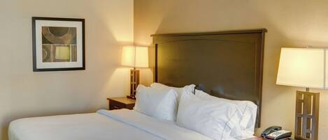 A hotel room with a bed, two bedside lamps, a framed picture on the wall, and a telephone on the nightstand.