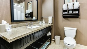A bathroom with a granite countertop sink, a mirror, a towel rack, a toilet, and a trash can. - Holiday Inn Express Hotel & Suites Huntsville by IHG (Huntsville)