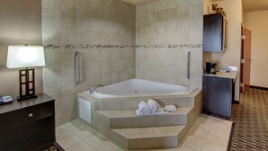 A modern bathroom with a large bathtub, a small sink, and a toilet. There are towels on the steps leading to the bathtub. - Holiday Inn Express Hotel & Suites Huntsville by IHG (Huntsville)