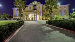 A Holiday Inn Express & Suites hotel with a central entrance, palm trees, and a parking lot. - Holiday Inn Express Hotel & Suites Huntsville by IHG (Huntsville)