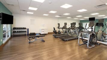 A fitness center with treadmills, elliptical machines, and dumbbells.