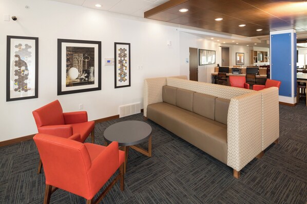 A modern lounge area with a sofa, chairs, and a small table.