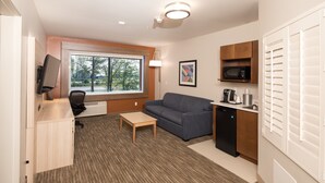 Un espacio habitable compacto con sofá, una mesita, kitchenette y televisor.