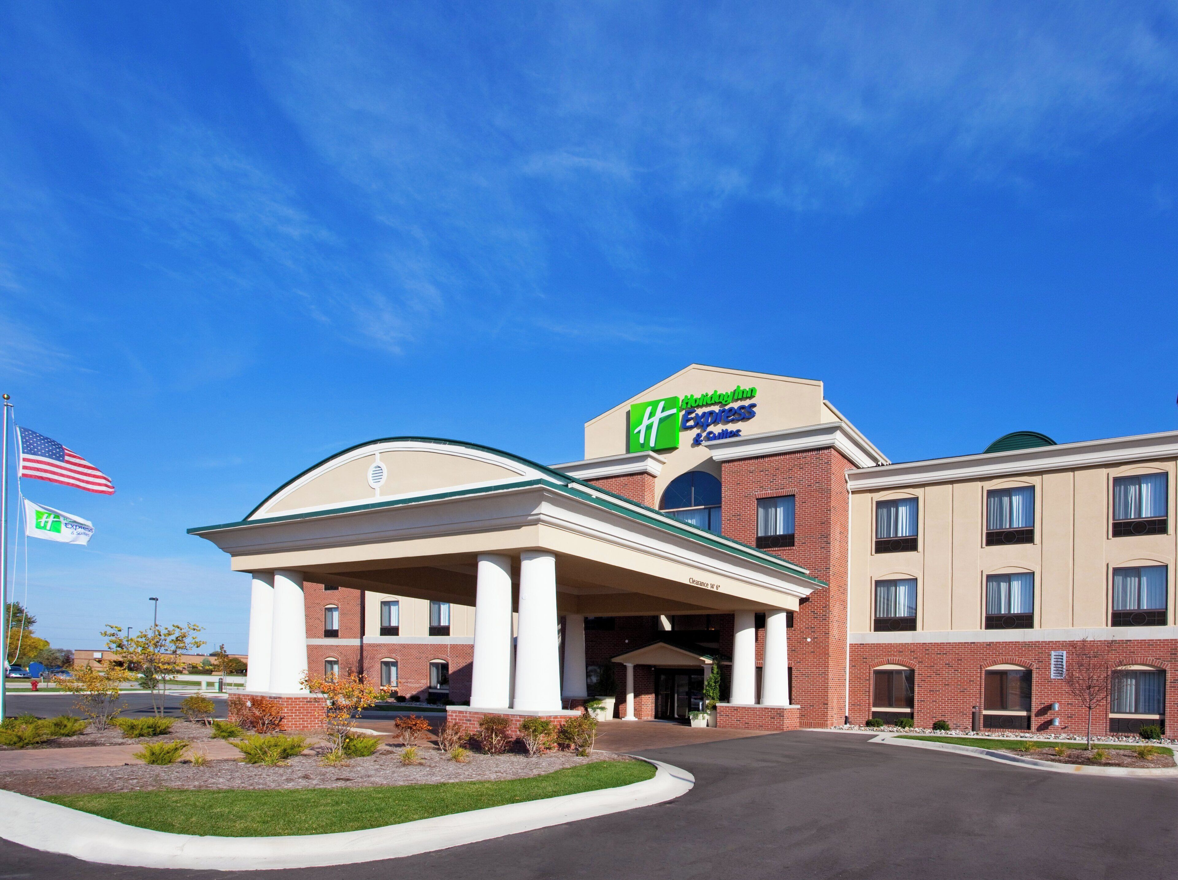 A hotel with a prominent 'Holiday Inn Express & Suites' sign, a covered entrance, and a brick facade.