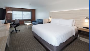 Una camera d'albergo con un letto grande, una scrivania con una sedia, un tavolino, un divano e una televisione.
