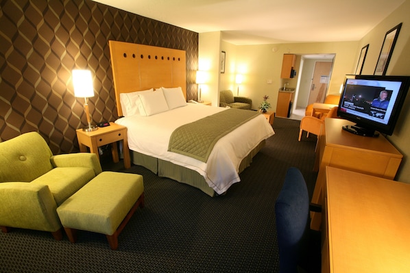 A hotel room with a bed, a desk, a television, a chair, and a small table.