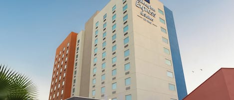 Un hotel de varios pisos con un cartel llamativo de Holiday Inn Express & Suites by IHG.