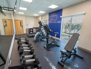 Un gimnasio con cintas de correr, elípticas y pesas sueltas.