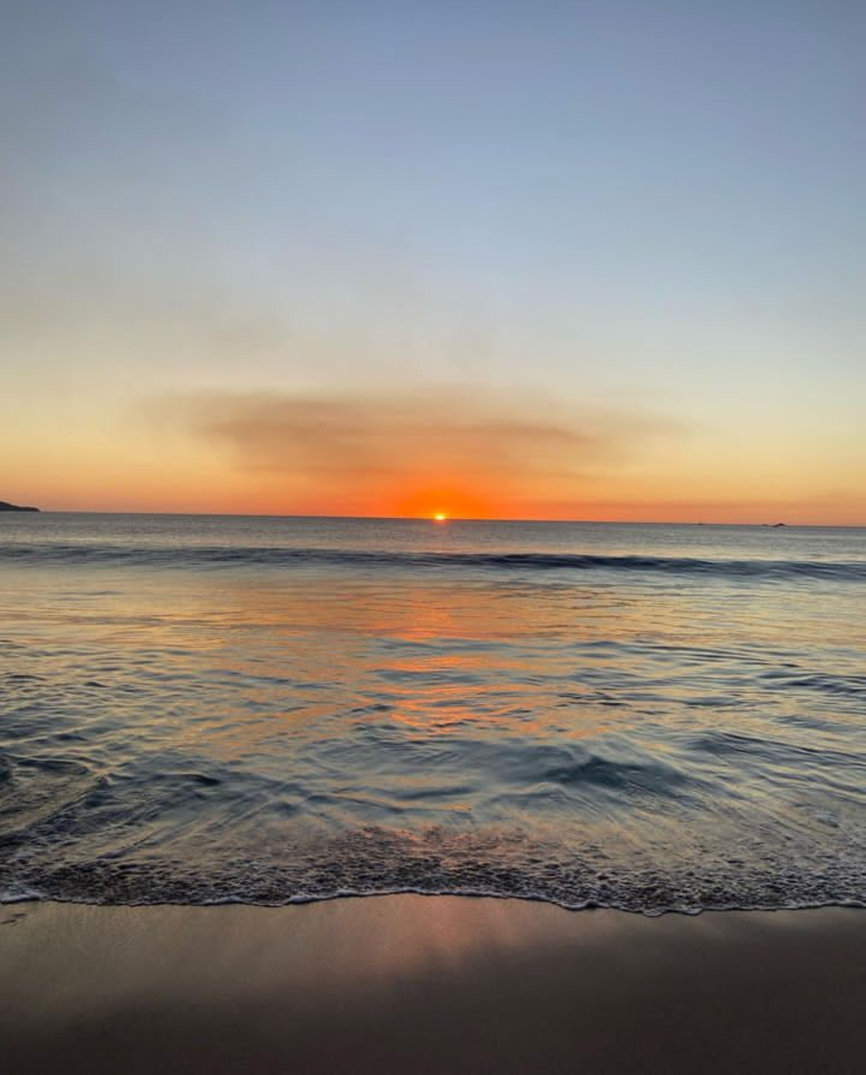 A beach with calm waters and a sunset.