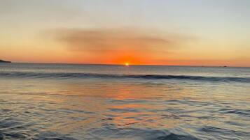 Una playa con aguas tranquilas y un atardecer.
