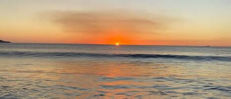 A beach with calm waters and a sunset.