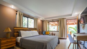 A bedroom with a large bed, bedside tables, a desk, and chairs. - Hotel Arco Iris (Tamarindo)