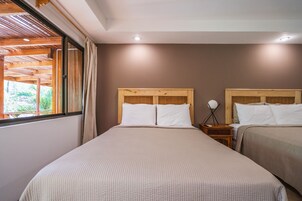 Quarto com duas camas, cabeceiras de madeira e janela com cortinas.