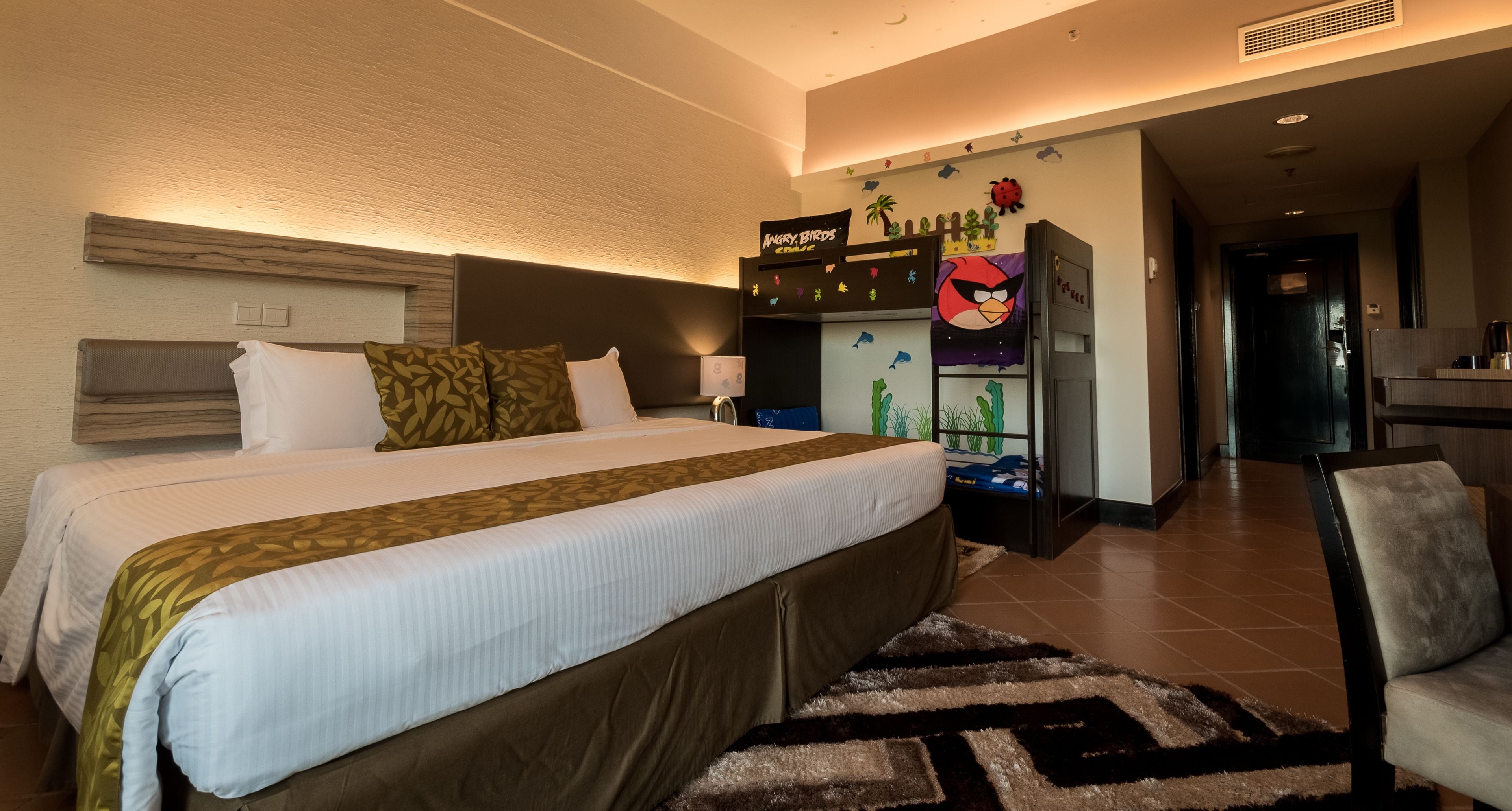Habitación de hotel con una cama grande, un escritorio y una silla. Hay un adorno en la pared con personajes de Angry Birds.