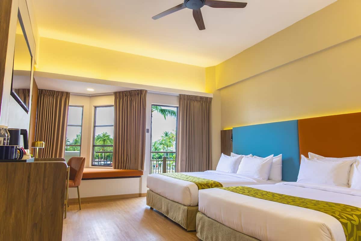 A hotel room with two beds, a desk, a chair, and a balcony with curtains.