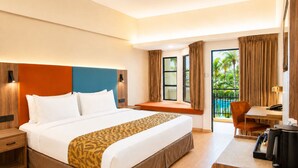 A hotel room with a bed, a desk, a chair, a coffee maker, and a view of a pool. - Thistle Port Dickson (Port Dickson)